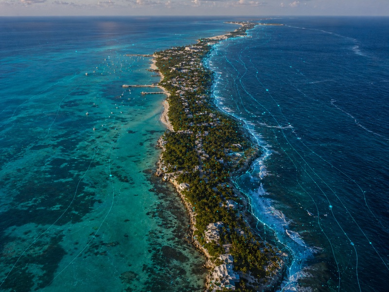 Vista aérea de Isla Mujeres con agua turquesa y trazos de datos en la costa